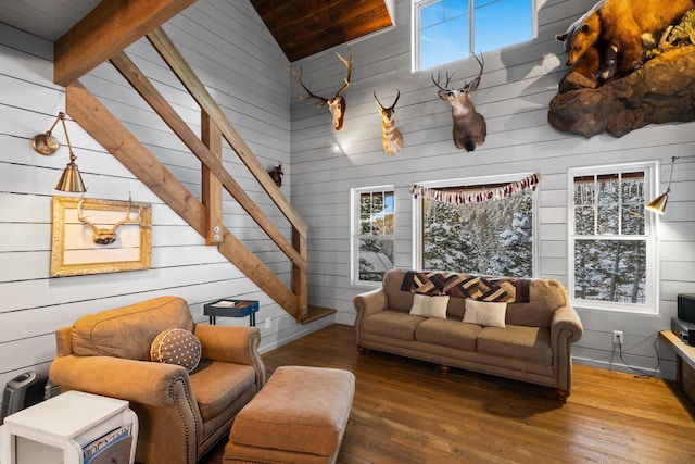 living area featuring high vaulted ceiling, stairway, wood finished floors, and a healthy amount of sunlight