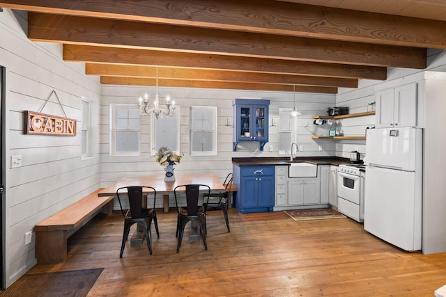 kitchen featuring decorative light fixtures, dark countertops, a sink, blue cabinets, and white appliances