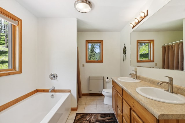 bathroom featuring tile floors, dual sinks, a wealth of natural light, and toilet