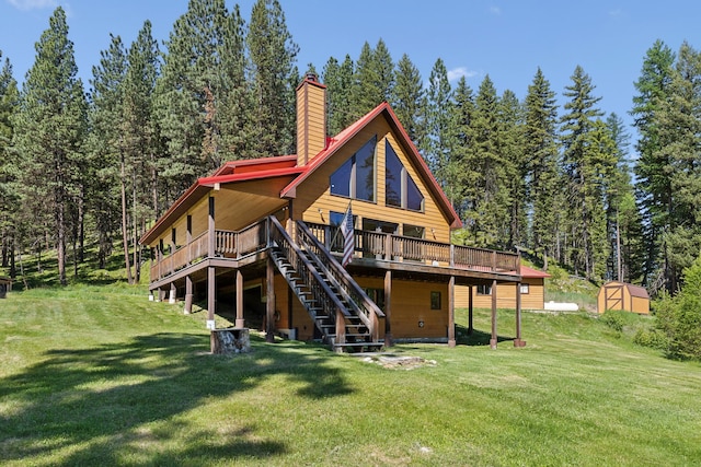 rear view of house with a deck, a storage shed, and a yard