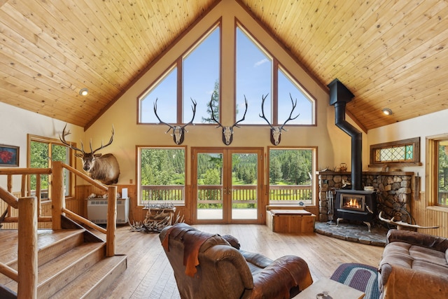 living room with high vaulted ceiling, light hardwood / wood-style flooring, a wood stove, and wood ceiling