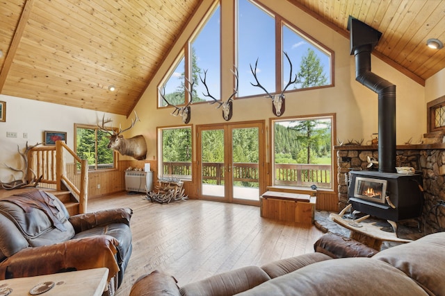 living room featuring plenty of natural light, a wood stove, and wooden ceiling