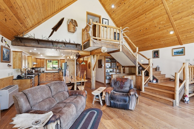 living room with a towering ceiling, light hardwood / wood-style floors, an inviting chandelier, and wooden ceiling