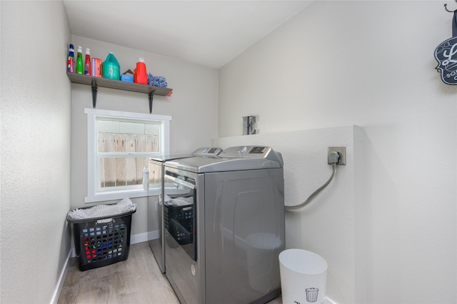 clothes washing area featuring light hardwood / wood-style flooring and washing machine and dryer