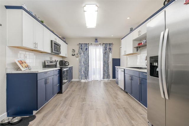 kitchen with decorative backsplash, white cabinets, and stainless steel appliances