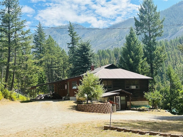 8 Cedar Gulch Ln, Thompson Falls, MT 59873 - view of front of house with a wooded view, dirt driveway, a mountain view, and a carport