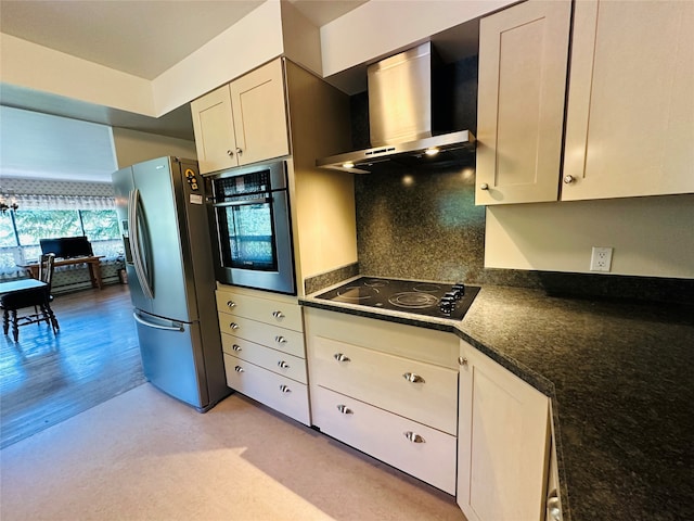 kitchen with wall chimney exhaust hood, appliances with stainless steel finishes, and dark stone counters