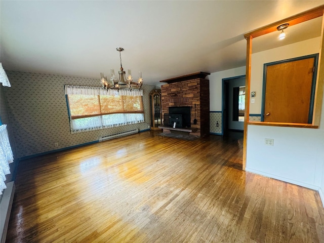 8 Cedar Gulch Ln, Thompson Falls, MT 59873 - unfurnished living room featuring wood finished floors, a chandelier, healthy amount of natural light, wallpapered walls, and a fireplace