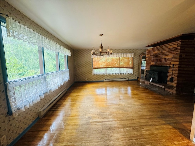 8 Cedar Gulch Ln, Thompson Falls, MT 59873 - unfurnished living room with a baseboard radiator, wallpapered walls, a chandelier, wood finished floors, and a large fireplace
