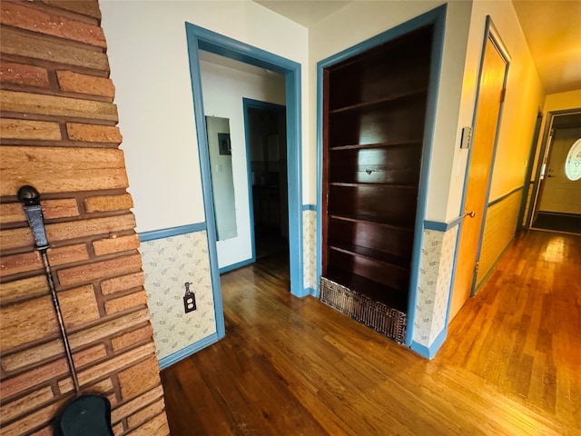 hallway with built in shelves and dark wood-type flooring