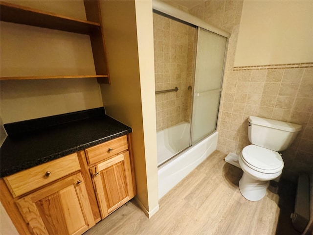 8 Cedar Gulch Ln, Thompson Falls, MT 59873 - bathroom featuring wood finished floors, combined bath / shower with glass door, tile walls, a wainscoted wall, and vanity