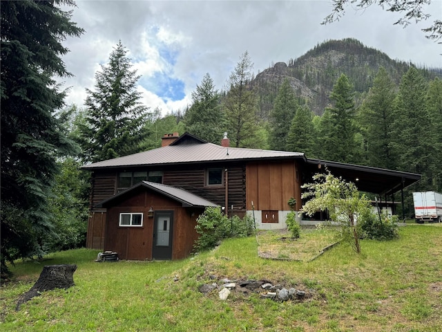 8 Cedar Gulch Ln, Thompson Falls, MT 59873 - back of property with a chimney, a yard, a mountain view, and log siding