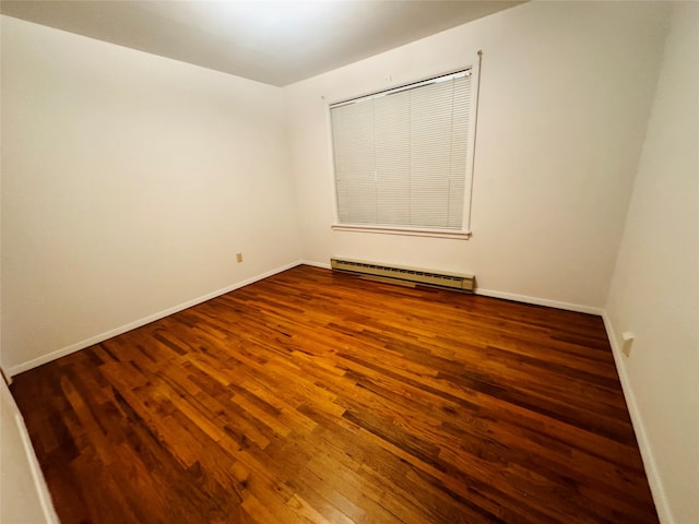 empty room with dark hardwood / wood-style flooring and baseboard heating