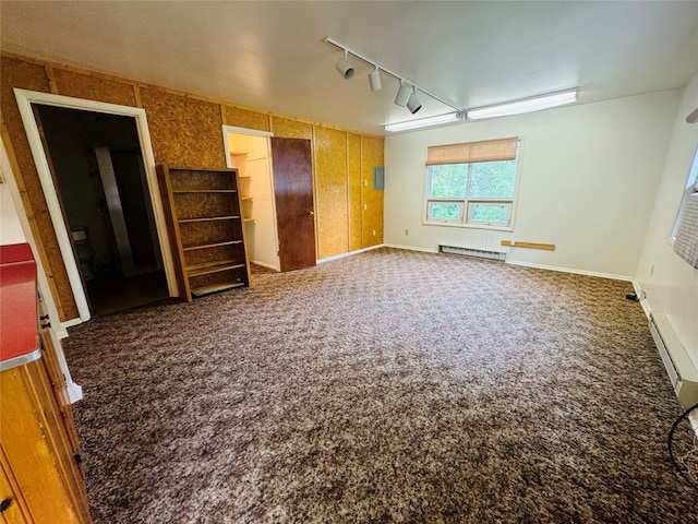 unfurnished bedroom with a closet, baseboard heating, rail lighting, and carpet floors