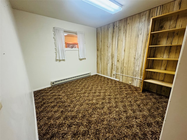 carpeted spare room with wooden walls and a baseboard heating unit