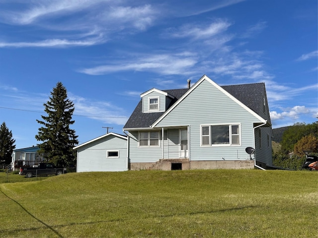 back of property featuring a shingled roof and a lawn