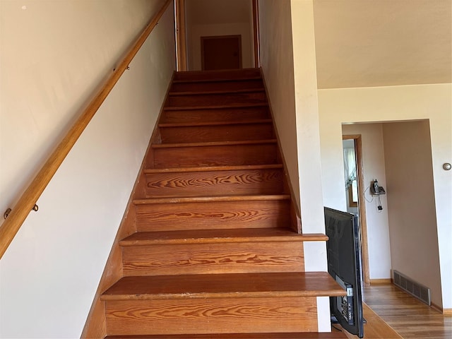 stairs with visible vents and wood finished floors