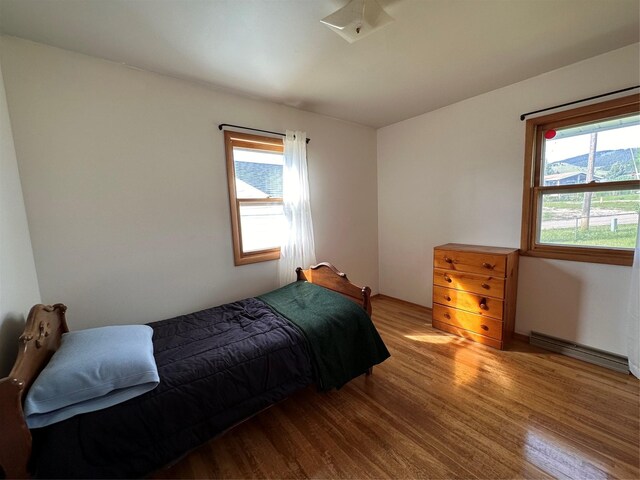 bedroom with baseboard heating and wood finished floors