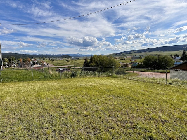 view of yard with a rural view, a mountain view, and fence