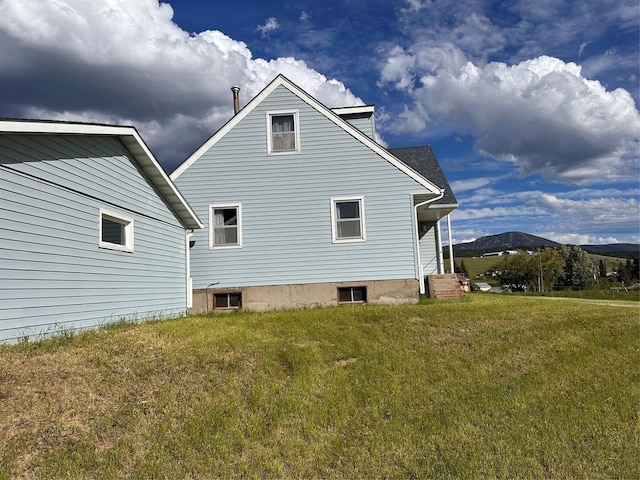 view of side of property featuring a mountain view and a lawn