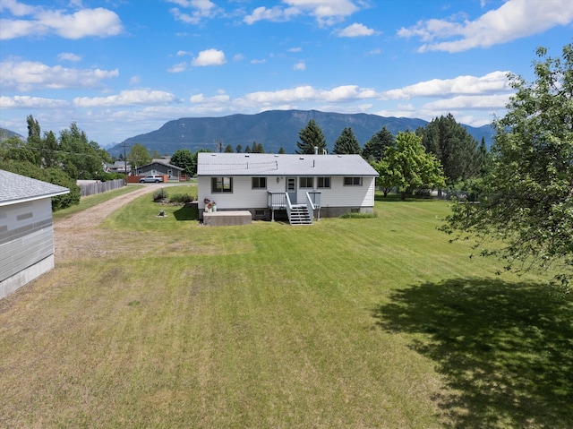 back of property featuring a deck with mountain view and a lawn