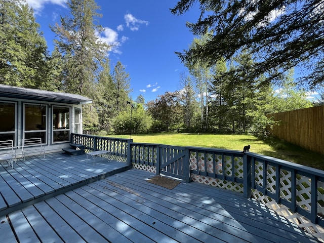 wooden terrace featuring a sunroom and a lawn