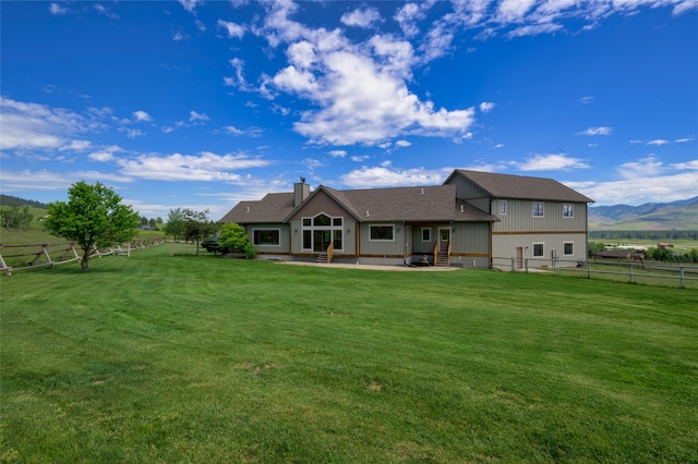 back of property featuring a mountain view, a patio area, and a lawn