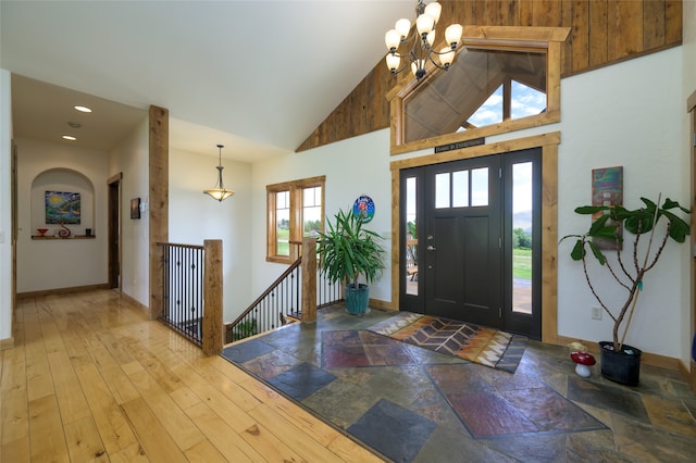 foyer featuring a notable chandelier, wood-type flooring, and high vaulted ceiling