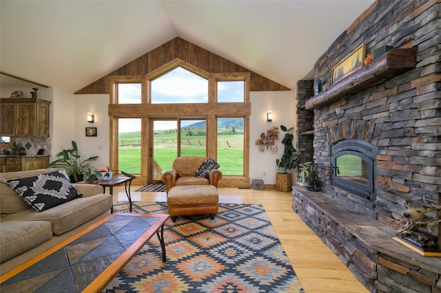 living room with a stone fireplace, wood-type flooring, and high vaulted ceiling