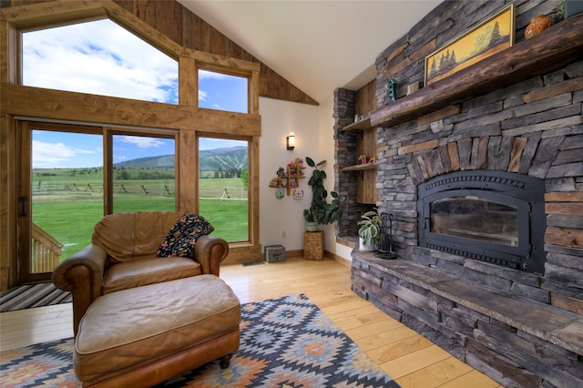 living room featuring plenty of natural light, high vaulted ceiling, a fireplace, and hardwood / wood-style flooring