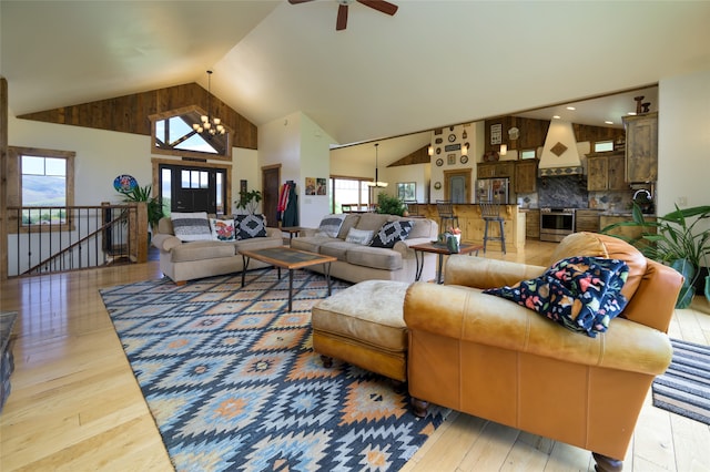 living room featuring ceiling fan with notable chandelier, hardwood / wood-style flooring, and high vaulted ceiling