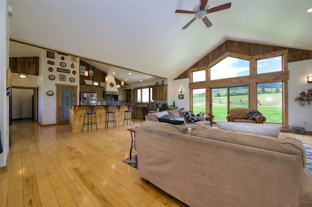 living room featuring light hardwood / wood-style flooring, ceiling fan, and high vaulted ceiling