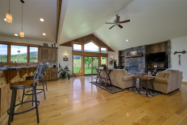 living room featuring light hardwood / wood-style floors, a large fireplace, high vaulted ceiling, and a healthy amount of sunlight