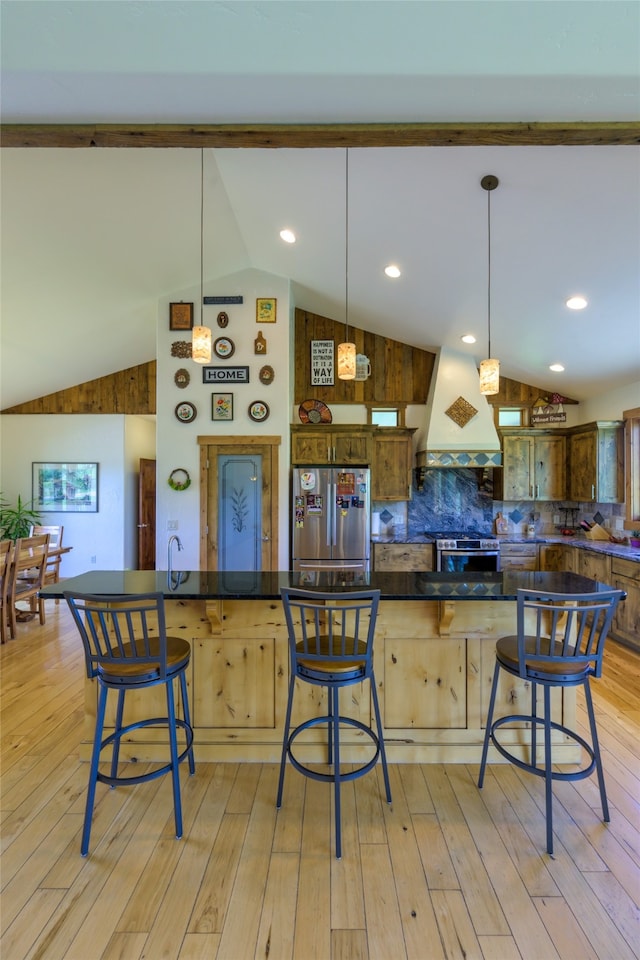 kitchen with appliances with stainless steel finishes, light wood-type flooring, lofted ceiling, and custom exhaust hood