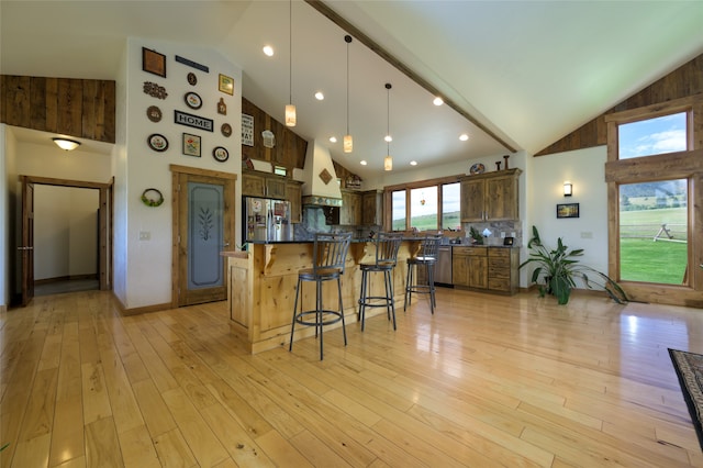 kitchen featuring stainless steel refrigerator with ice dispenser, custom exhaust hood, light wood-type flooring, and high vaulted ceiling