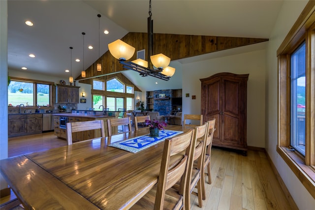 dining space featuring light hardwood / wood-style floors, high vaulted ceiling, sink, and an inviting chandelier