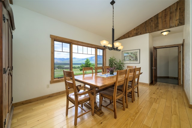 dining area with light hardwood / wood-style floors, an inviting chandelier, a mountain view, and high vaulted ceiling