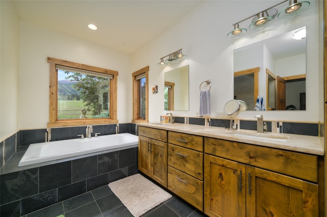 bathroom featuring tiled tub, tile patterned floors, and double sink vanity