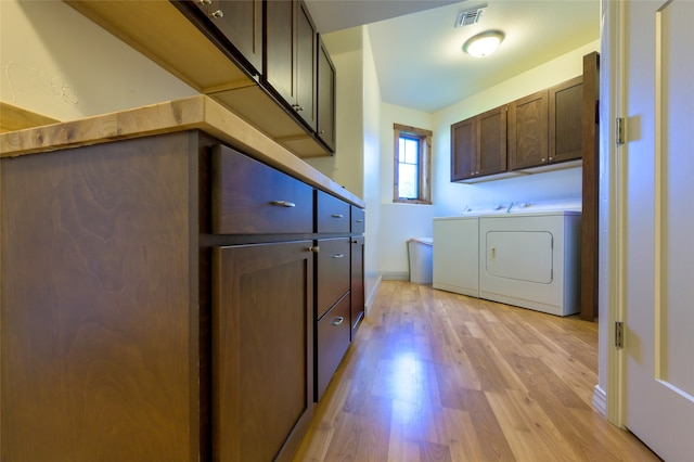 laundry room with cabinets, washer and clothes dryer, and light wood-type flooring