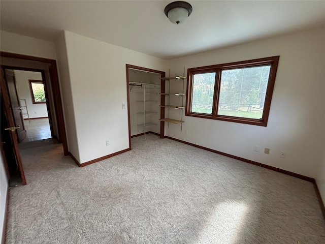 unfurnished bedroom with light colored carpet and a closet