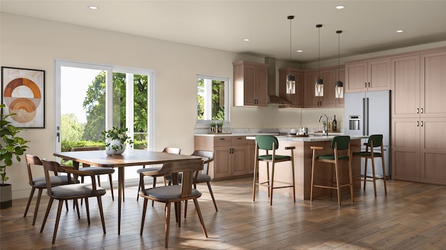 kitchen with wall chimney exhaust hood, a kitchen island, wood-type flooring, decorative light fixtures, and sink