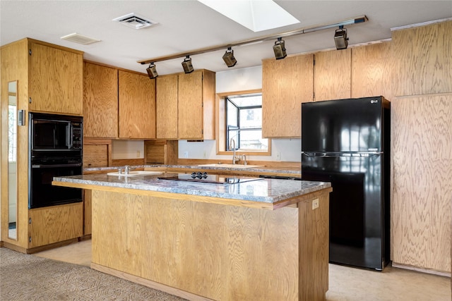 kitchen featuring a skylight, sink, a kitchen island, and black appliances