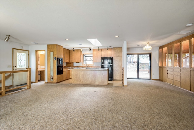 kitchen with light carpet, a healthy amount of sunlight, and black appliances