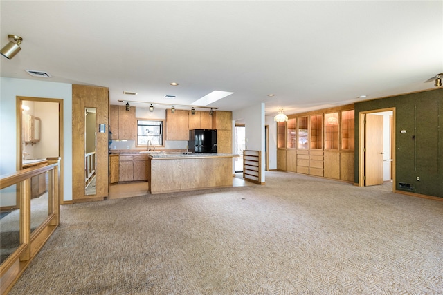 kitchen with light colored carpet, black refrigerator, and sink