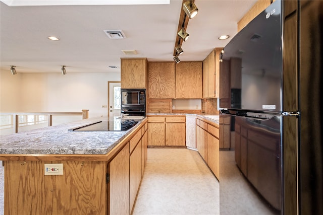 kitchen with light carpet, black appliances, track lighting, and a kitchen island