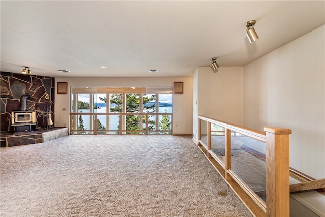 unfurnished living room featuring carpet floors and a wood stove