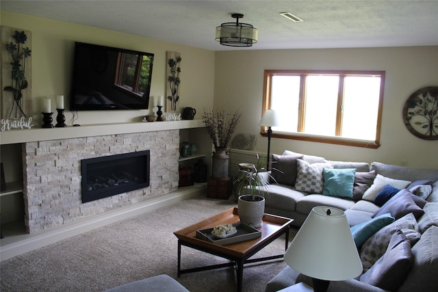 living room with carpet flooring, a textured ceiling, and a stone fireplace