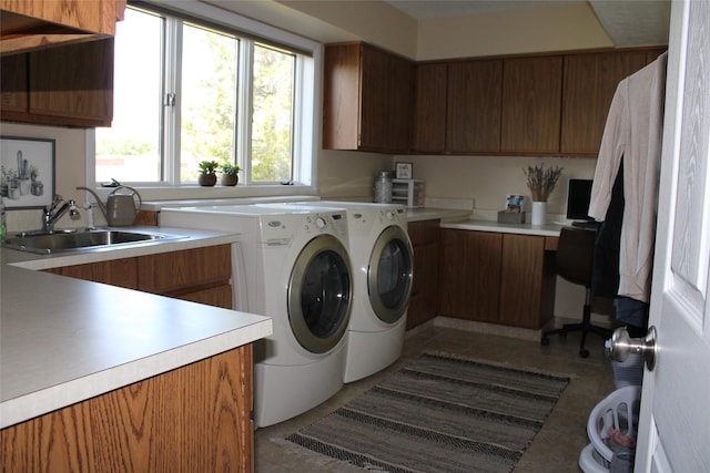 laundry area featuring cabinets, dark tile patterned flooring, washing machine and clothes dryer, and sink