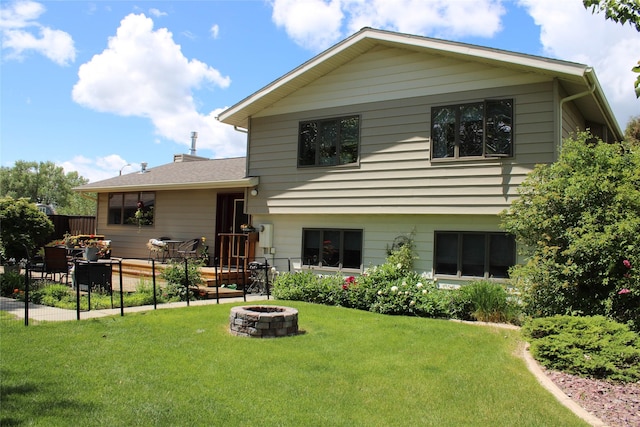 back of house with a fire pit and a lawn