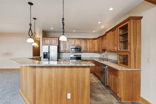 kitchen with a sink, a kitchen island, hanging light fixtures, appliances with stainless steel finishes, and glass insert cabinets